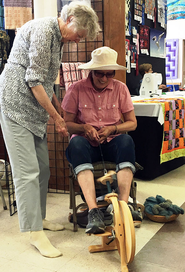 Cecelia teaching spinning at the Fair